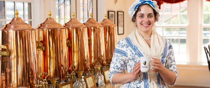 Photo of woman standing in front 5 tea dispensers